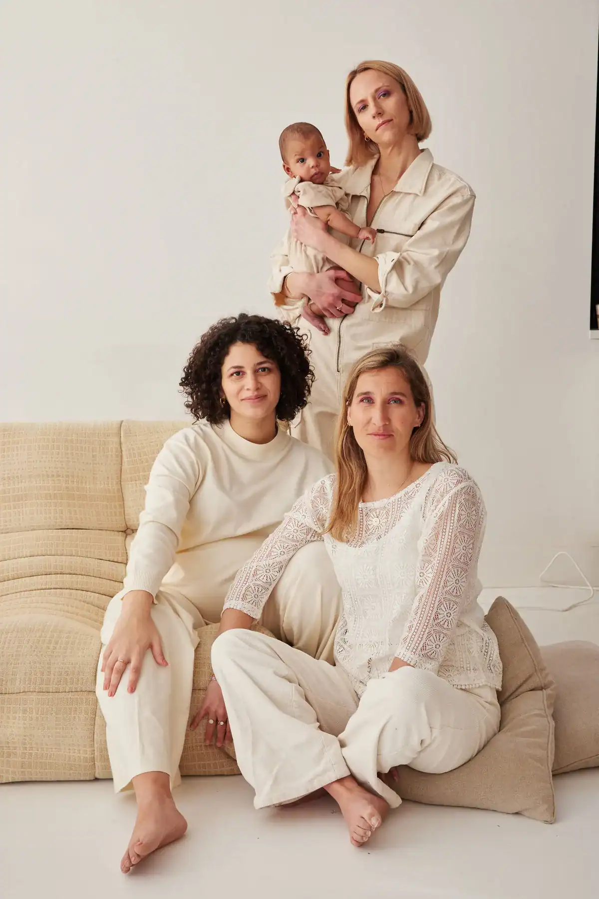Trois femmes et un bébé en tenues claires, guides grossesse et post-partum Holi Mama