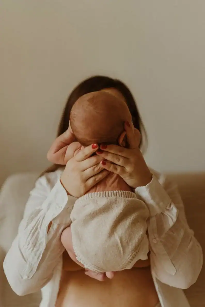 Jeune mère tenant son nouveau-né contre elle, ebook de recettes post-partum Holi Mama